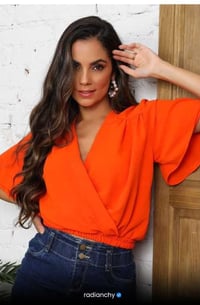 a woman in a bright orange top and jeans