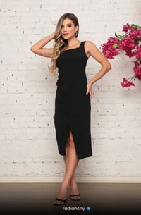 a woman in a black dress standing in front of a white brick wall