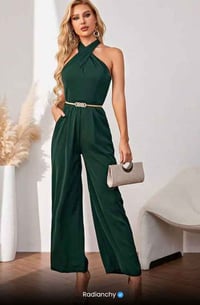a woman wearing a green jumpsuit with a clutch bag
