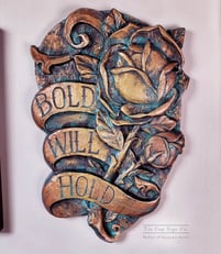 A plaque in the style of traditional tattoo art. A rose with a banner that says Bold Will Hold. 