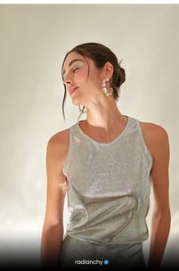 a woman with a silver top and earrings
