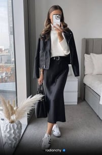 a woman in a black leather jacket and white sneakers