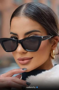a woman with a cat eye sunglasses and a fur coat