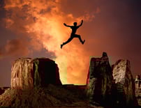 Silhouette jumping over rocks, representing breaking through personal barriers