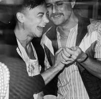 black & white image of friends laughing heartily and holding each other