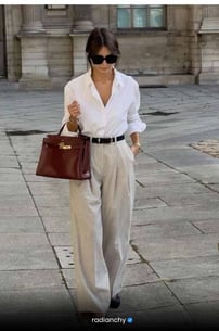 a woman in a white shirt and pants with a brown bag