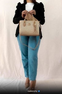 a woman in jeans and a white shirt is holding a purse