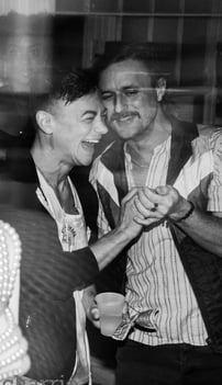 black & white image of friends laughing heartily and holding each other