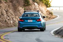 a blue car driving down a curve in the road