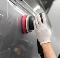 a person wearing gloves and gloves while polishing a car