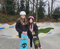 two girls holding a skateboard