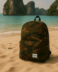 a Herschel camo backpack sitting on the sand of a beach in Thailand