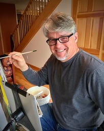 an artist smiling and holding a paintbrush