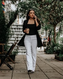 uma mulher caminhando pela calçada com uma xícara de café