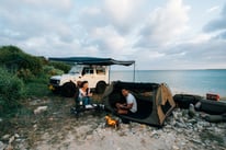 Couple enjoying a campfire and tent setup next to their Suzuki Jimny by the ocean in Okinawa | Evertrail Okinawa