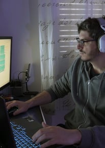 a man wearing headphones and headphones, sitting at a desk with a laptop