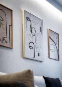 Una sala de estar con cuadros, un sofá y una planta.