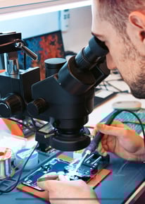 a man in a black shirt is looking at a microscope