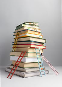 a stack of books with a ladder up to the top of it