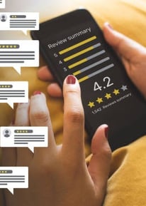 Person monitoring and managing online reviews and customer feedback on a mobile phone.