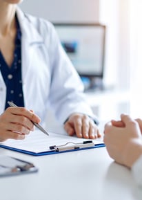 Médico mujer dando consulta con pluma en la mano