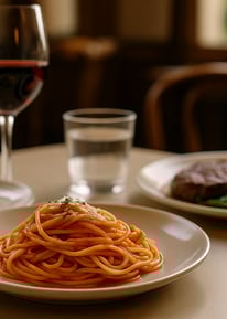 a plate of spaghetti pasta with a glass of wine