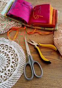 Napperon au crochet posé sur une table des ciseaux une pince des aiguilles à coudre dans un étui