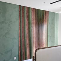 Modern green limewash accent wall featuring a vertical wood detail, creating a stylish and natural focal point.