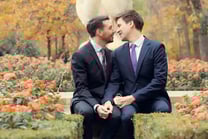 "Pareja gay casada mirándose con amor en Madrid, celebrando su boda y su conexión."
