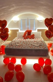 Romantic surprise room setup with heart-shaped balloons for an anniversary celebration.