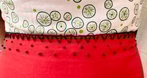 Embroidered waist of a white, green, and red strappy sundress