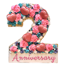 Cookie cake decorated with chocolate buttercream, topped with assorted chocolates and French macarons for celebrations