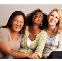 Three ethically diverse women sitting close together and laughing.