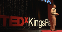a woman standing on a stage making a TEDx speech