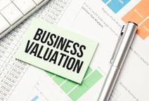 Hand holding a scale balancing coins and a business model.