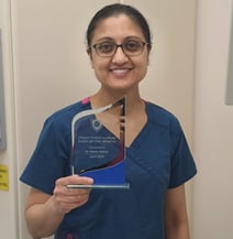 a lady dentist in scrubs and holding a trophy