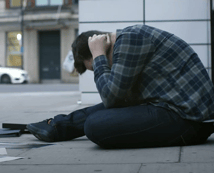 a man sitting on the sidewalk in front of a building