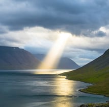 sun beam coming through clouds onto ocean