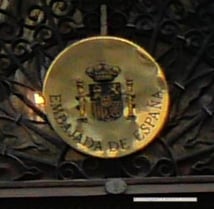 A golden emblem of Embajada de Espana with Spanish coats-of-armsh brown 