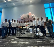 a group of men standing around a table with balloons