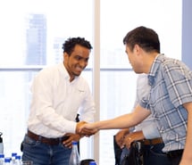 a man shaking hands with another man in a room