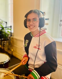 a woman in a white jacket and headphones playing drums