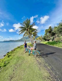 Eva et Manon en vélo devant des palmiers et le lagon bleu de Bora