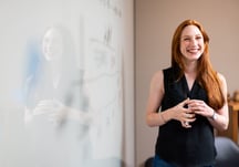 Woman smiling standing in front of a white board