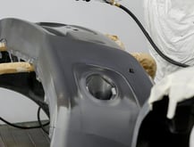 a man in a white suit and a white coat painting a car at fix collision center