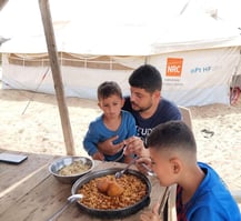 a man and two boys eating food at a table