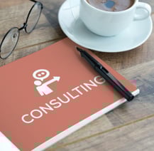 The image of the notebook titled "CONSULTING" with glasses, a pen, and a coffee cup.