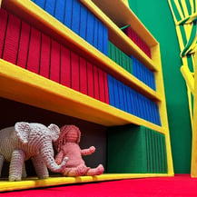 A crocheted elephant and doll sit on a bookshelf in Goodnight Moon - A Fiber Tale by Dundee & Lee artists Odeile & Chapin.