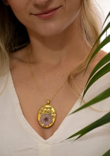 A happy customer wearing a resin floral necklace from Elfin Forest, smiling in natural sunlight.