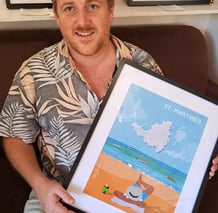 Artist smiling while holding a framed beach-themed print titled "Cloud Spotting"